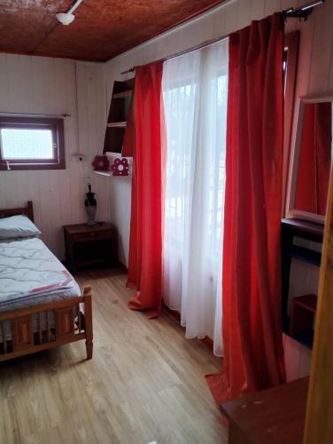 a bedroom with red and white curtains and a bed at Hospedaje Alondra in Osorno