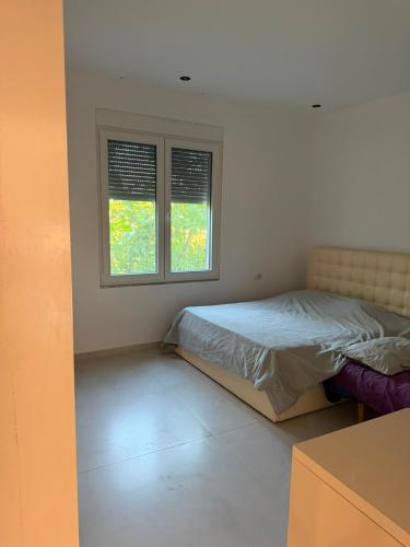 a bedroom with a bed and two windows at Villa Hasani in Hamallë
