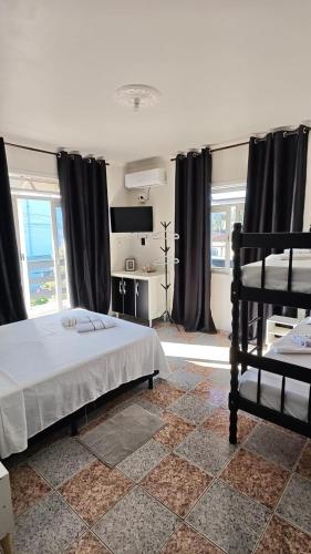a bedroom with a bed and a tv and windows at Casa temporada in Joinville