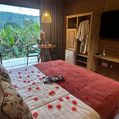a bedroom with a bed with red flowers on it at Chalés Ceuci in Santo Antônio do Pinhal