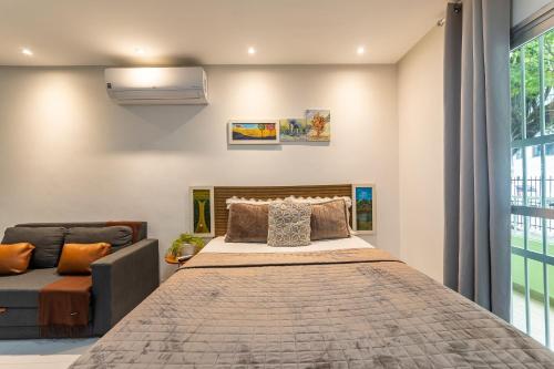 a bedroom with a large bed and a couch at Apartamentos com internet rápida in Maceió