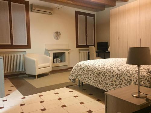 1 dormitorio con 1 cama, 1 silla y chimenea en B&B Via Garibaldi, en Lonigo