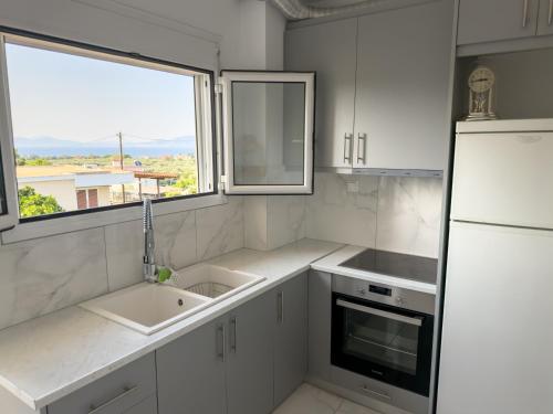 a white kitchen with a sink and a refrigerator at Modern Sea View Apartment - Arkitsa Rentals in Arkitsa