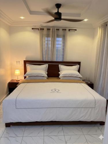 a bedroom with a large white bed with a ceiling at Asibbey Lodge in Ashalebotwe