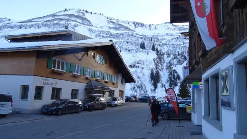 a person walking down a street next to a mountain at Pension Edelweiss in Damuls