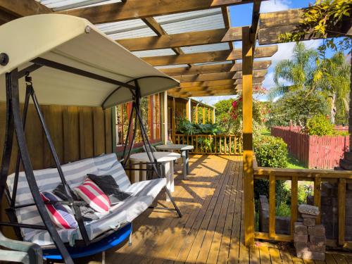a porch with a swing and a pergola at Relax a Lodge in Kerikeri