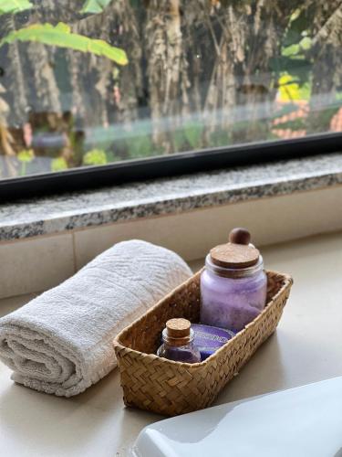 a basket of towels and two jars on a window sill at Chalés Ceuci in Santo Antônio do Pinhal
