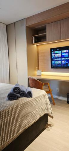 a bedroom with a bed and a flat screen tv at Apê Brisa-5min consulado EUA-garagem in Porto Alegre