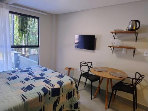 a bedroom with a bed and a table and a tv at Villa Parati Bombinhas Sob Nova Direção in Bombinhas