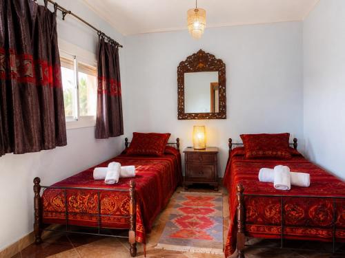 a bedroom with two beds and a mirror on the wall at Desert Stars Oasis in Aoufous