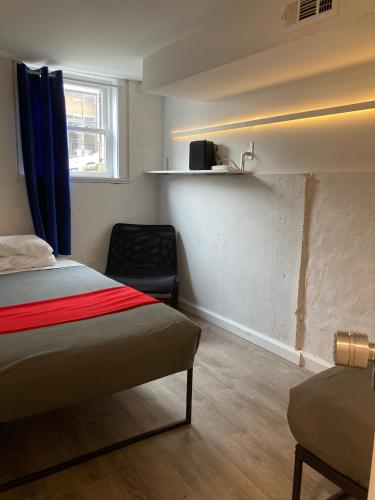 a bedroom with a bed and a chair in a room at Modern GuestHouse Ironbound Newark with KITCHEN-FastTrainToNYC-OneStopToAirport in Newark