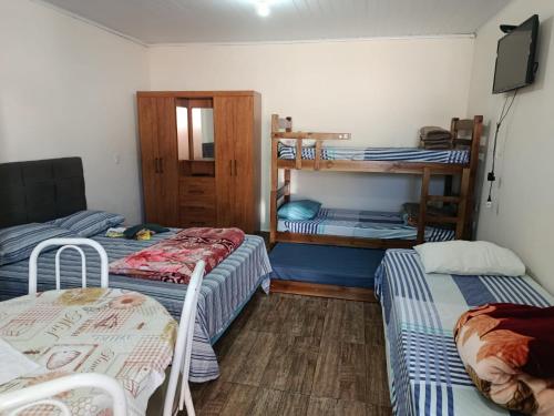 a room with three bunk beds and a television at Pousada Paraiso in Telêmaco Borba