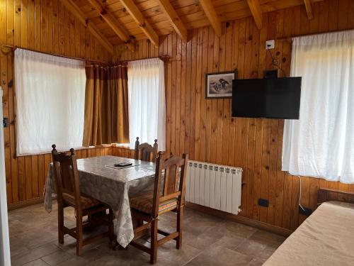 a dining room with a table and chairs and a television at Illihue - Cabañas, Hostería & Spa in Junín de los Andes