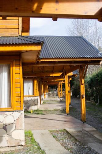 a wooden building with a black roof and a walkway at Illihue - Cabañas, Hostería & Spa in Junín de los Andes