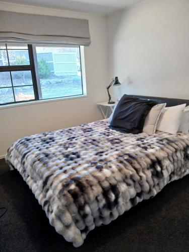 a bedroom with a large bed with a large window at Cardrona mountain cottage in Cardrona