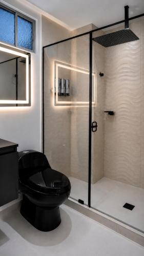a bathroom with a black toilet and a shower at Aparta Estudios Luz Galery in Bogotá