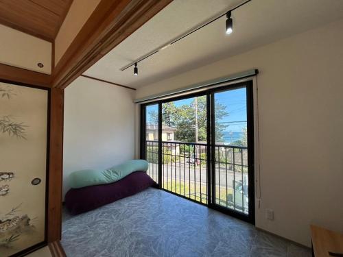 a room with a large window with a bed and a balcony at Sea Retreat Nika in Kawazu