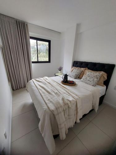 a white bedroom with a large white bed with a window at Condomínio Sol Marina in Camaçari
