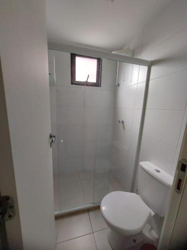 a white bathroom with a shower and a toilet at Condomínio Sol Marina in Camaçari