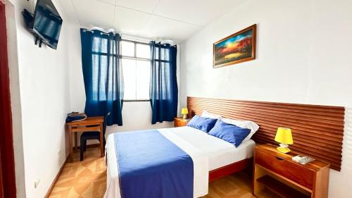 a bedroom with a bed and a desk and a window at Hostal Maravilla Amazónica in Iquitos