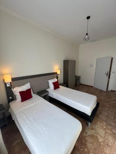 two beds in a hotel room with red pillows at Chambre meublée in Nice