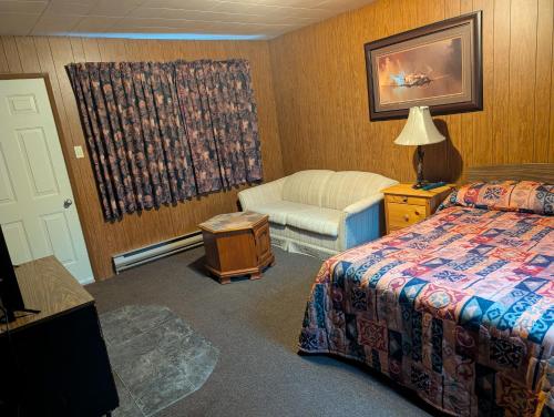 a hotel room with a bed and a chair at Lang's Motel in Wabigoon