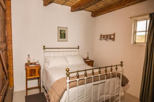 a bedroom with a white bed and a window at Matjiesvlei Guestfarm in Calitzdorp