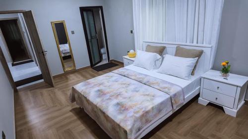 a bedroom with a large white bed and a mirror at The Rehoboth in Sakumona