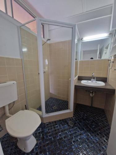 a bathroom with a shower and a toilet and a sink at Hilltop Hotel in Goonellabah