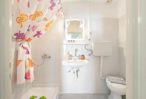a bathroom with a sink and a toilet and a shower curtain at Akteon Rooms in Agia Galini