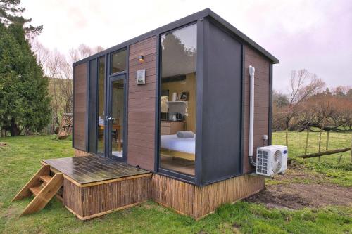 a tiny house with a bedroom in a field at Wahi Marie X by Tiny Away in Puketitiri