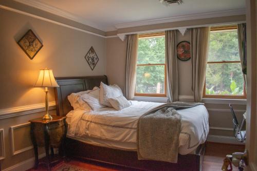 a bedroom with a bed and two windows at National Harbor Guesthouse in Fort Washington