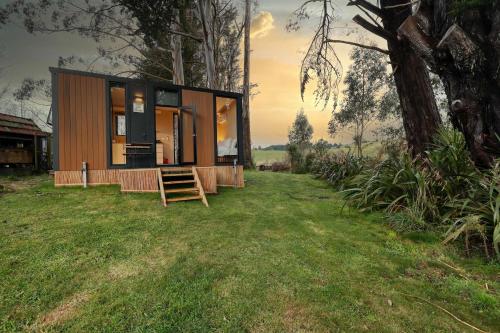 a small house in a field with a tree at Wahi Marie X by Tiny Away in Puketitiri