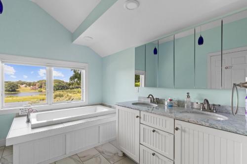 ein Badezimmer mit zwei Waschbecken, einer Badewanne und einem Fenster in der Unterkunft Salmon River View in Pulaski