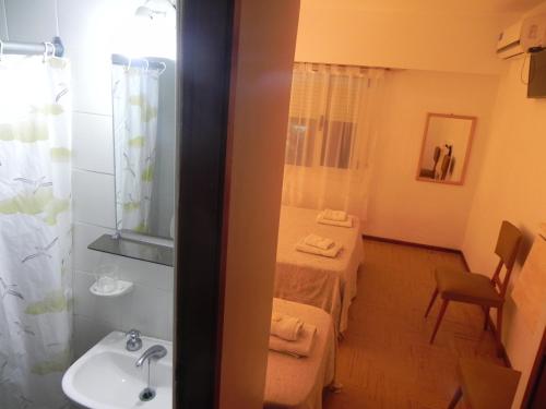 una habitación con un baño con lavabo y una cama en Hotel Tritones, en Pinamar