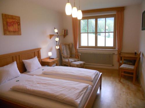 ein Schlafzimmer mit einem Bett, einem Stuhl und einem Fenster in der Unterkunft Haus Pürcher in Bad Mitterndorf