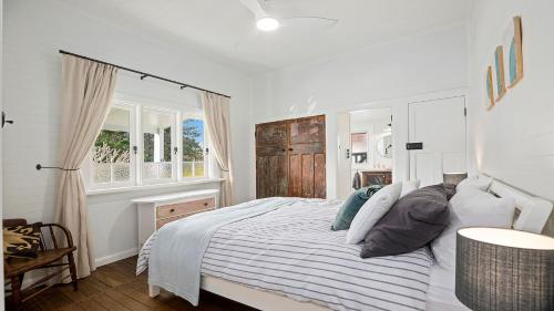 a white bedroom with a bed with a striped blanket at 19 Newry St in Nambucca Heads