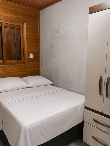 two beds in a small bedroom with wooden walls at Kitnet Completa Próx Unipampa e Centro Wi-Fi in Alegrete