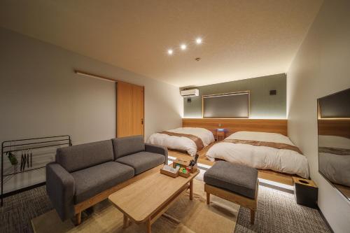 a hotel room with two beds and a couch at 別府の宿 結 -Yui- in Beppu
