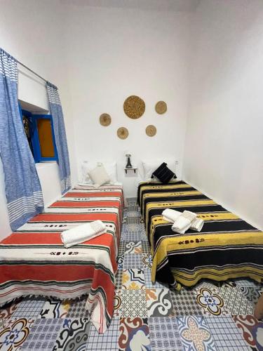 two beds in a room with colorful blankets at Riad hotel borj in Tétouan