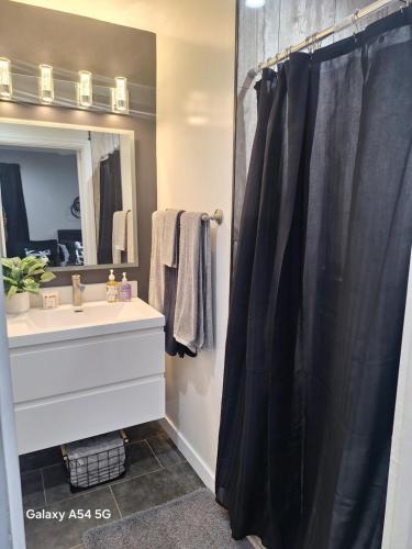 a bathroom with a black shower curtain and a sink at Beautiful studio in Azusa