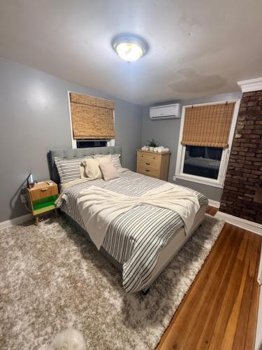 a bedroom with a large bed and two windows at Grey comfort room in New London