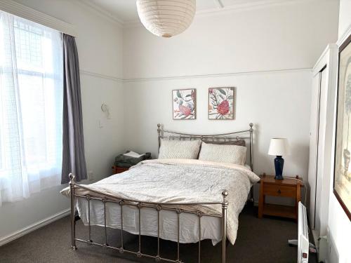 a white bedroom with a bed and a window at Pretty Villa Close to St Clair Beach private parking in Dunedin
