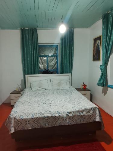 a bedroom with a bed with green curtains and a window at Madriel Eko Retreat in Bokonbayevo