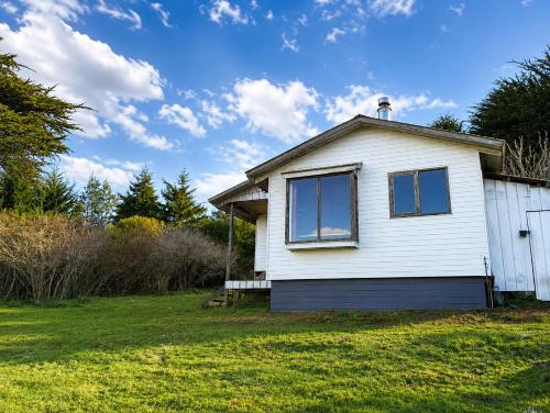 a white house with windows on a yard at El Urco Chiloé - Cabaña Guapilacuy in Ancud