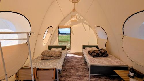 a tent with two beds in it with a window at Guest House of Issyk-Kul Camp in Chok-Tal