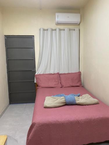 a bed in a room with a pink blanket at Apartamento Colinas in Cacoal