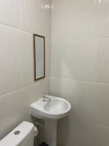 a white bathroom with a sink and a toilet at Apartamento Colinas in Cacoal