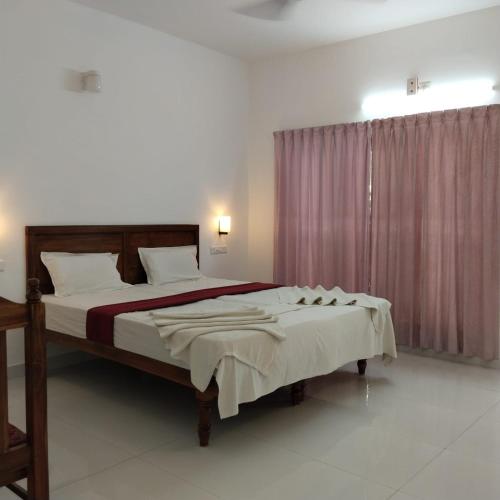 a bedroom with a large bed and a window at Hotel Neptune Kovalam in Trivandrum