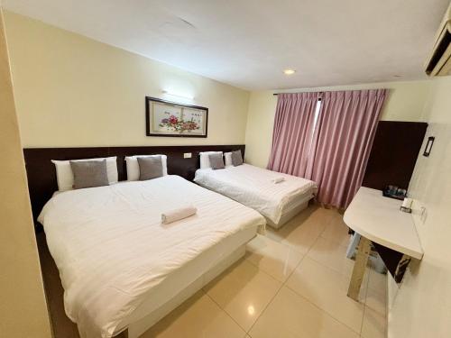 a hotel room with two beds and a desk at Happiness Hotel in Kulai